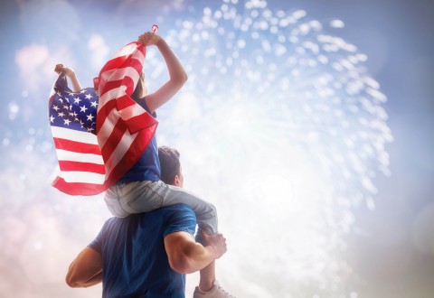 Dad and child watching fireworks holding a US flag