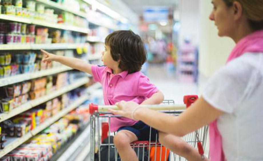Child in shopping cart pointing to items