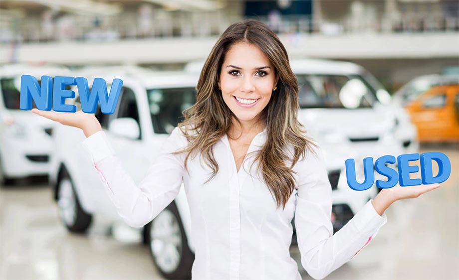 Woman holding the words NEW and USED in front of cars
